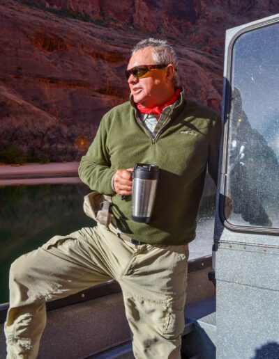 terry gunn Man holding mug on boat by canyon cliff.