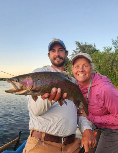 wendy gunn Two people holding trout by river.